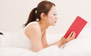 female with a mask on her face while reading a book