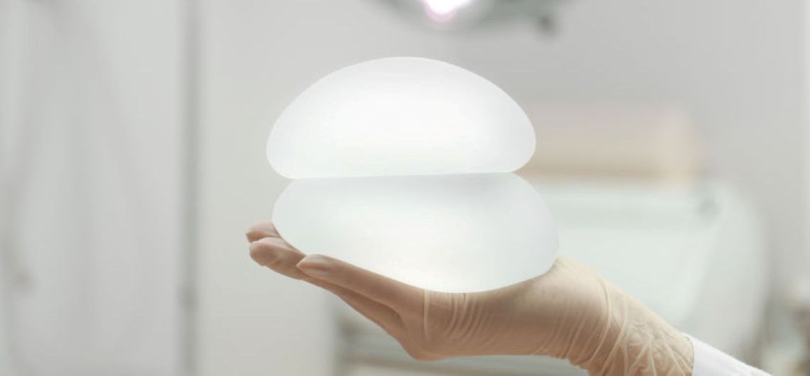 hand holding two breast implants in a clinic setting